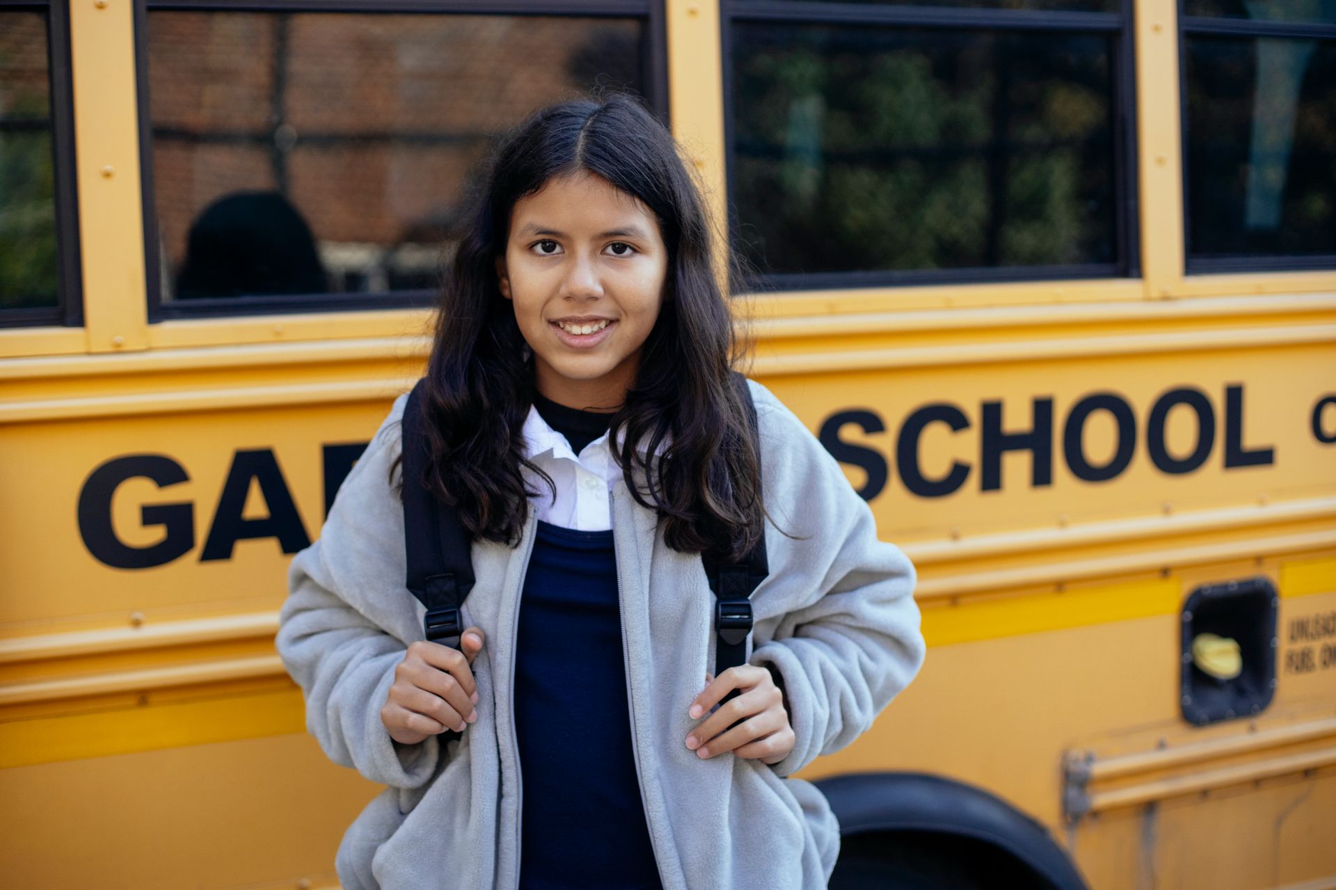 Estudiante con maleta junto al transporte escolar